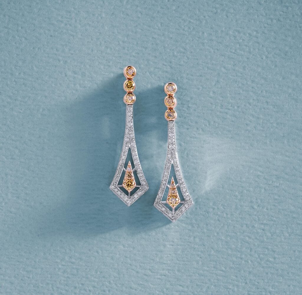 Beautiful diamond earrings displayed on a baby blue textured surface, highlighting luxury and elegance.